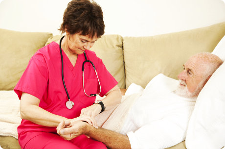 Home health nurse taking the pulse of an elderly patient