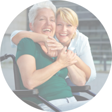 Smiling disabled senior women in wheelchair with extended care nurse