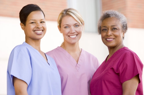 nurses standing outside a hospital smiling